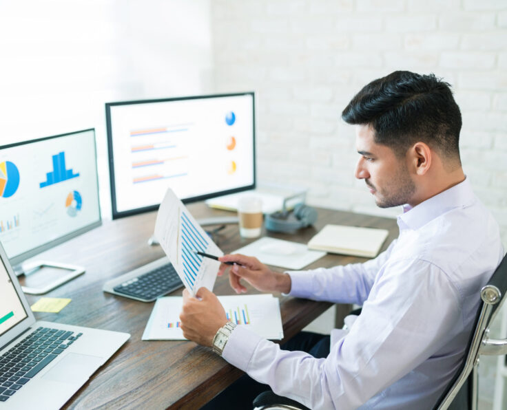 Handsome Latin businessman examining sales data while working at home